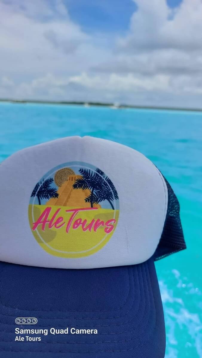 Gorra de Ale Tours sobre el agua turquesa de Bacalar